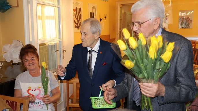 Seniorzy z DDP przy ul. Narutowicza obchodzili Dzień Kobiet - Seniorzy wręczają kwaity z okazji Dnia Kobiet