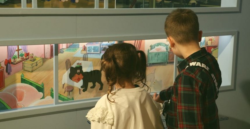 Dziewczynka z chłopcem w muzeum oglądają obrazki przez szybę