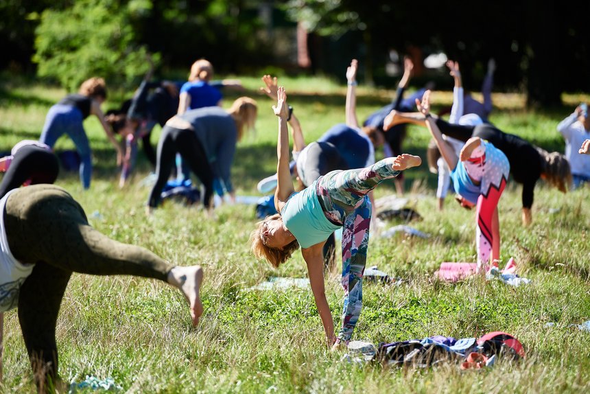 Ludzie uprawiający jogę na trawniku w parku