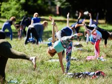 Ludzie uprawiający jogę na trawniku w parku
