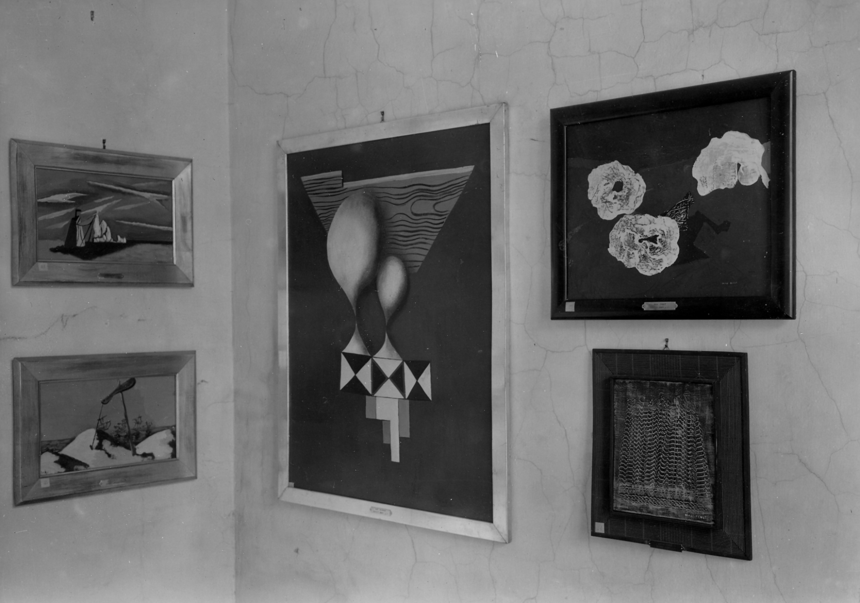 Czarnobiałe zdjęcie. W rogu ścian wisi pięć obrazów.