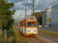 Na zdjęciu białopomarańczowy tramwaj lini turystycznej "0" jadący po torowisku. 
