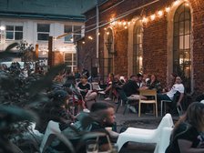 Ludzie siedzący przed lokalem przy stolikach wieczorem