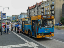 Na zdjęciu widać zabytkowy niebiesko-żółty autobus linii turystycznej "100" stojący na przystanku. Na przystanku znajdują się ludzie, którzy wsiadają do autobusu.