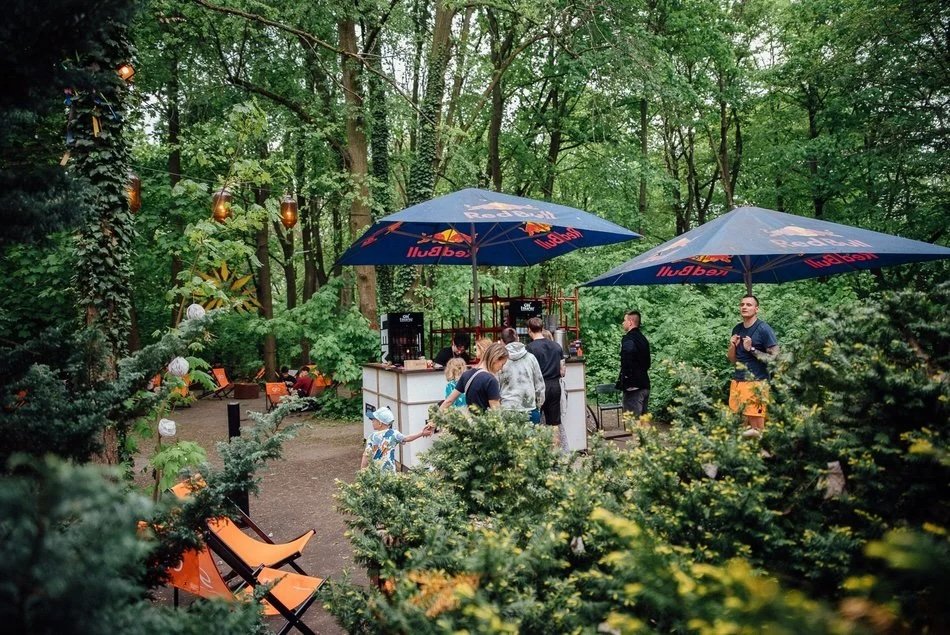  , Wyznaczona strefa gastronomiczna z leżakami i parasolami pośród gęstej zieleni parku Poniatowskiego
