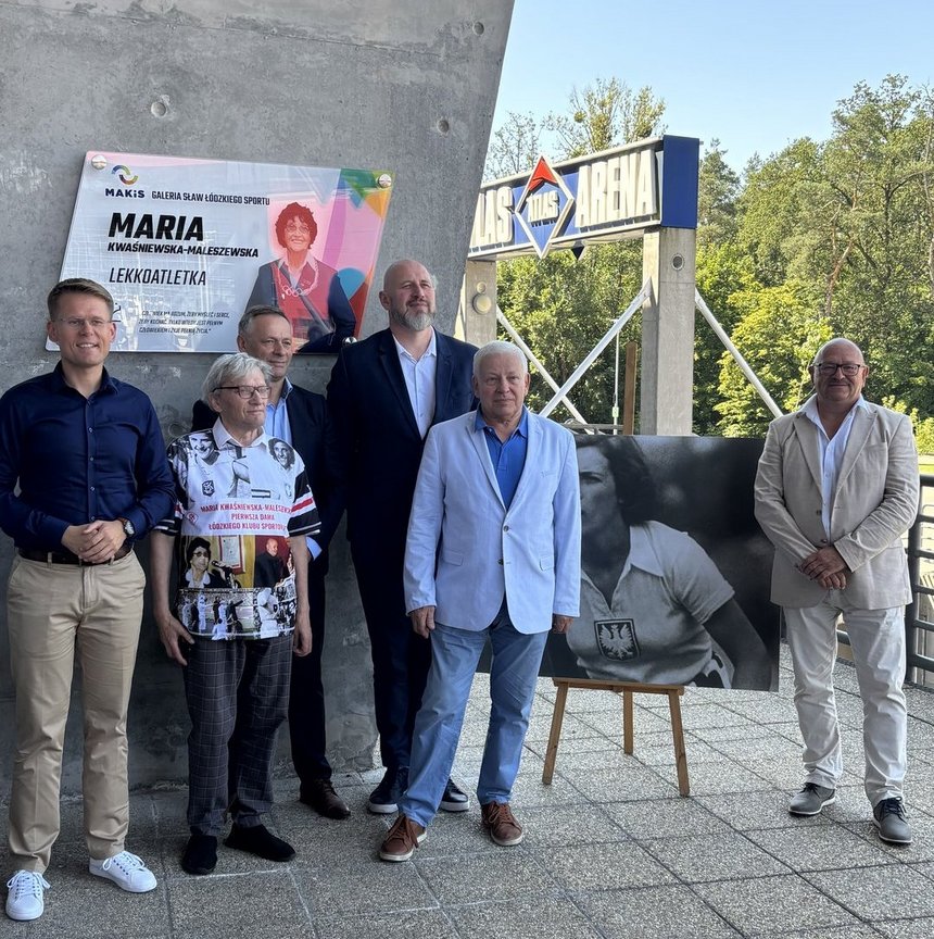 wspólne zdjęcie pod tablicą zaproszonych i przemawiających gości