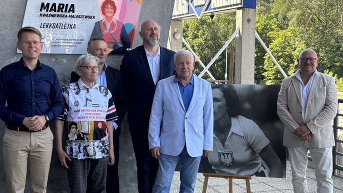  - wspólne zdjęcie pod tablicą zaproszonych i przemawiających gości