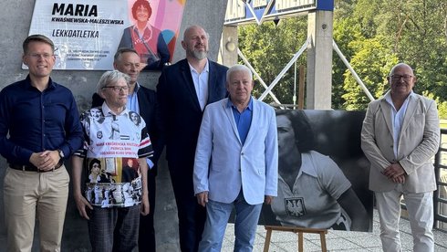 wspólne zdjęcie pod tablicą zaproszonych i przemawiających gości