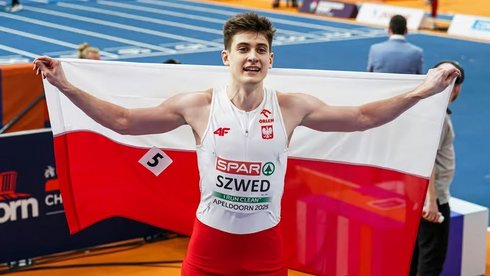 Maksymilian Szwed pozujący do zdjęcia z Polską flagą