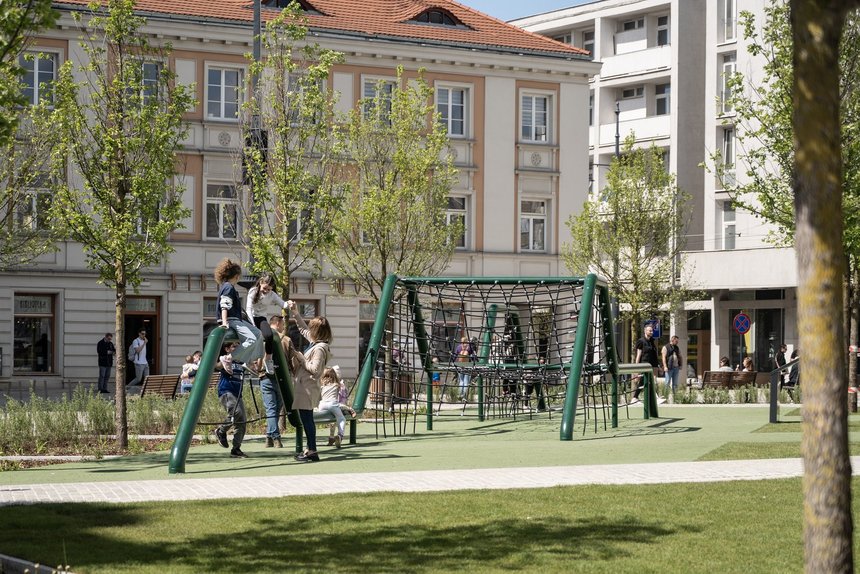 Dzieci z rodzicami bawiące się na placu zabaw na Placu Wolności