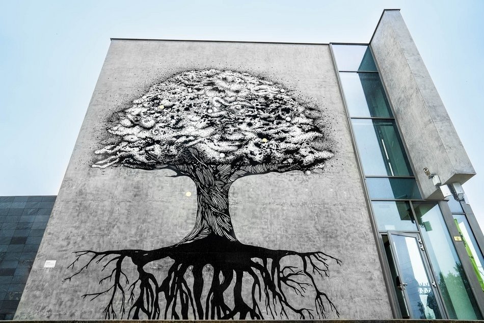  , Czarnobiały mural na szczycie budynku Centrum Dialogu przedstawiający drzewo wraz z jego czarnymi korzeniami 