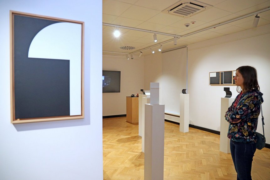 Kobieta przyglądająca się wystawie w Akademickim Centrum Designu. Na ścianach pomieszczenia wiszą obrazy.