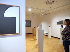 Kobieta przyglądająca się wystawie w Akademickim Centrum Designu. Na ścianach pomieszczenia wiszą obrazy.