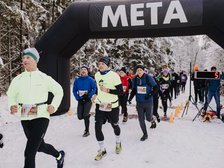 Grupa ludzi wbiega na metę po śniegu na tle zimowych drzew. Na górze zdjęcia napis Meta (biały na czarnym tle)