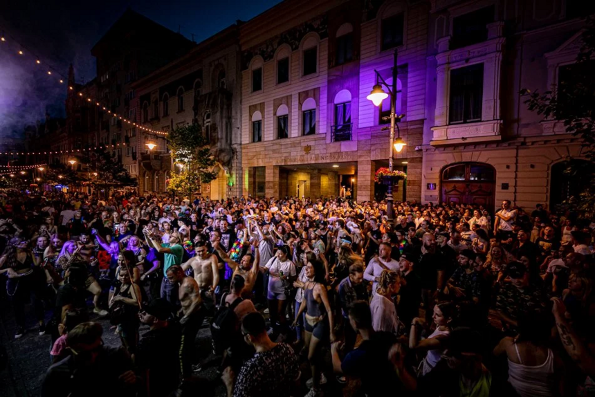 Wieczór. Fioletowe oświetlenia. Tłum ludzi na ulicy Piotrkowskiej.