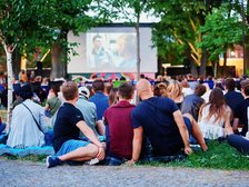 Ludzie siedzący na trawie podczas oglądania kina plenerowego na Księżym Młynie
