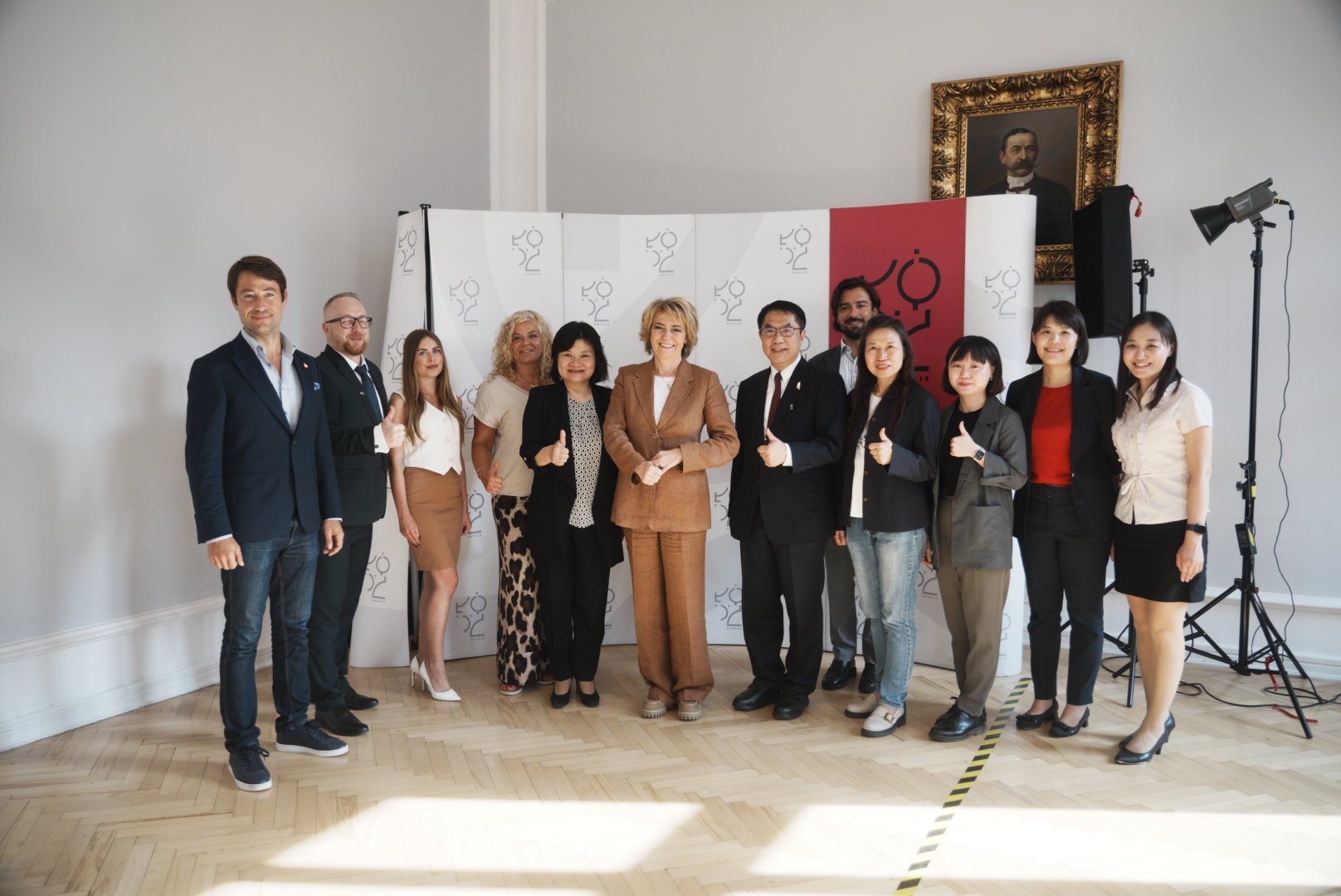 Przedstawiciele obu miast pozujący do zdjęcia z kciukiem w górze.