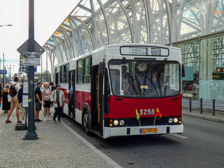 Na zdjęciu widać zabytkowy biało-czerwony autobus linii turystycznej "100" stojący na przystanku w centrum Łodzi. Na przystanku znajdują się ludzie, którzy wsiadają do autobusu.