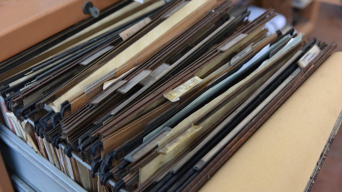 Pudło z dokumentami wypełnione brązowymi teczkami z danymi osobowymi. - Pudło z dokumentami wypełnione brązowymi teczkami z danymi osobowymi.