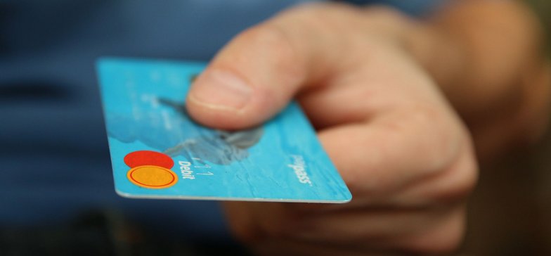 Zbliżenie na dłoń trzymającą kartę kredytową.