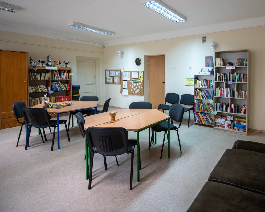 Ksiązkodzielnia przy ul. Kutrzeby 16. Przestronny pokój z regałami pełnymi książek pod ścianami oraz stołami z krzesłami po środku. 