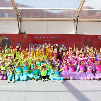 Ogromna grupa dzieci przebrana w kolorowe stroje do tańca pozuje z uśmiechem.