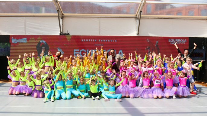 Ogromna grupa dzieci przebrana w kolorowe stroje do tańca pozuje z uśmiechem. - Ogromna grupa dzieci przebrana w kolorowe stroje do tańca pozuje z uśmiechem.