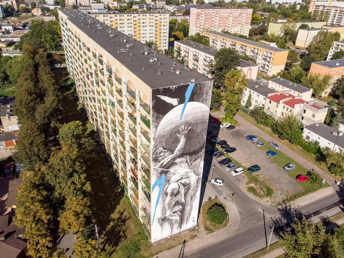 Mural na szczycie wieżowca przedstawiający postać greckiego boga Atlasa dźwigającego sklepienie niebieskie na własnych barkach.