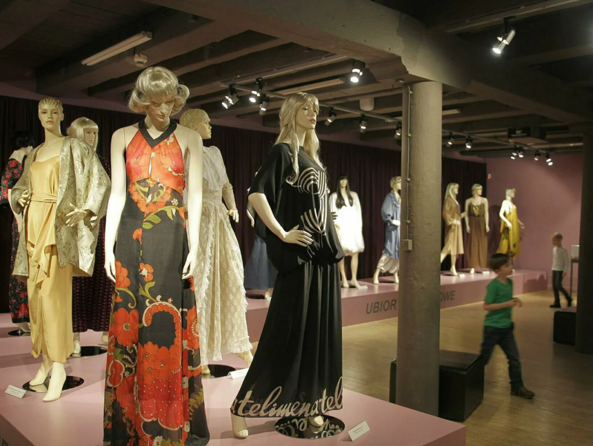 Wystawa w Muzeum Włókiennictwa. Wybieg dla modelek. Na wybiegu poustawiane kilkanaście kobiecych manekinów ubranych w sukienki o różnych krojach i kolorach.