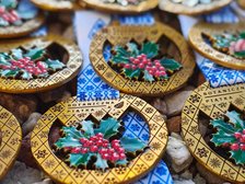 Zdjęcie przedstawia kolorowe medale w złotym kolorze z niebieską tasiemką. W centralnym punkcie medalu znajduje się zielony liść z owocami żurawiny.