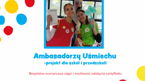 W centralnej części zdjęcia znajduje się fotografia dwóch osób, które są uśmiechnięte i pozują w kolorowych koszulkach – jedna w czerwonej, a druga w zielonej. Dookoła zdjęcia widnieją kolorowe kropki, tworzące radosny i przyjazny klimat. Na dole grafiki widnieje napis „Ambasadorzy Uśmiechu – projekt dla szkół i przedszkoli”, a poniżej informacji o bezpieczeństwie scenariuszy i możliwości zdobycia certyfikatu. Na samym dole znajduje się logo projektu, przedstawiające kolorowego klauna.