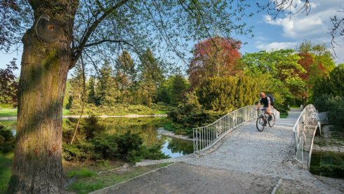 Rowerzysta przejeżdżający przez mostek w Parku Poniatowskiego
