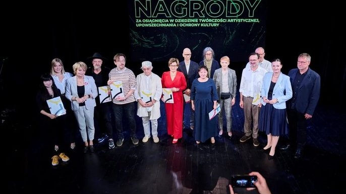  - Na scenie teatralnej stoi grupa ludzi. W dłoniach trzymają dyplomy. Są to laureaci nagród.