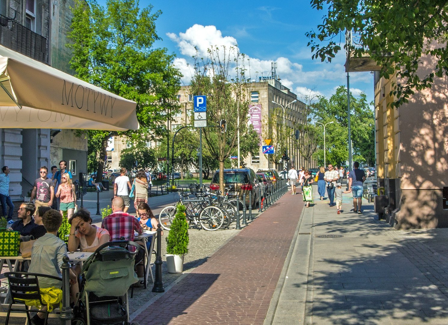 Ludzie idący i siedzący w ogródkach gastronomicznych