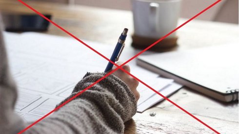 Na pierwszym planie ręka trzymająca długopis nad dokumentami położonymi na biurku. Dalej kubek z ciepłym napojem. Grafika jest przekreślona czerwonym znakiem X.
