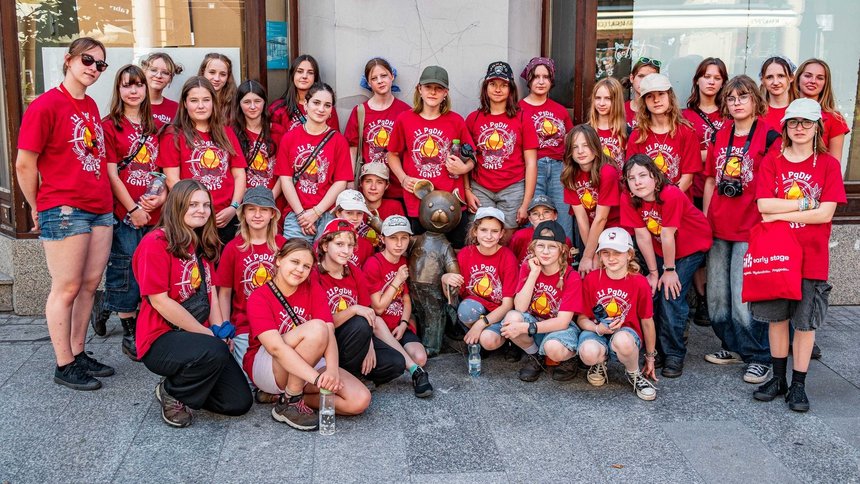 Na zdjęciu grupa młodzieży a w centrum grupy Rzeźba Misia Uszatka.